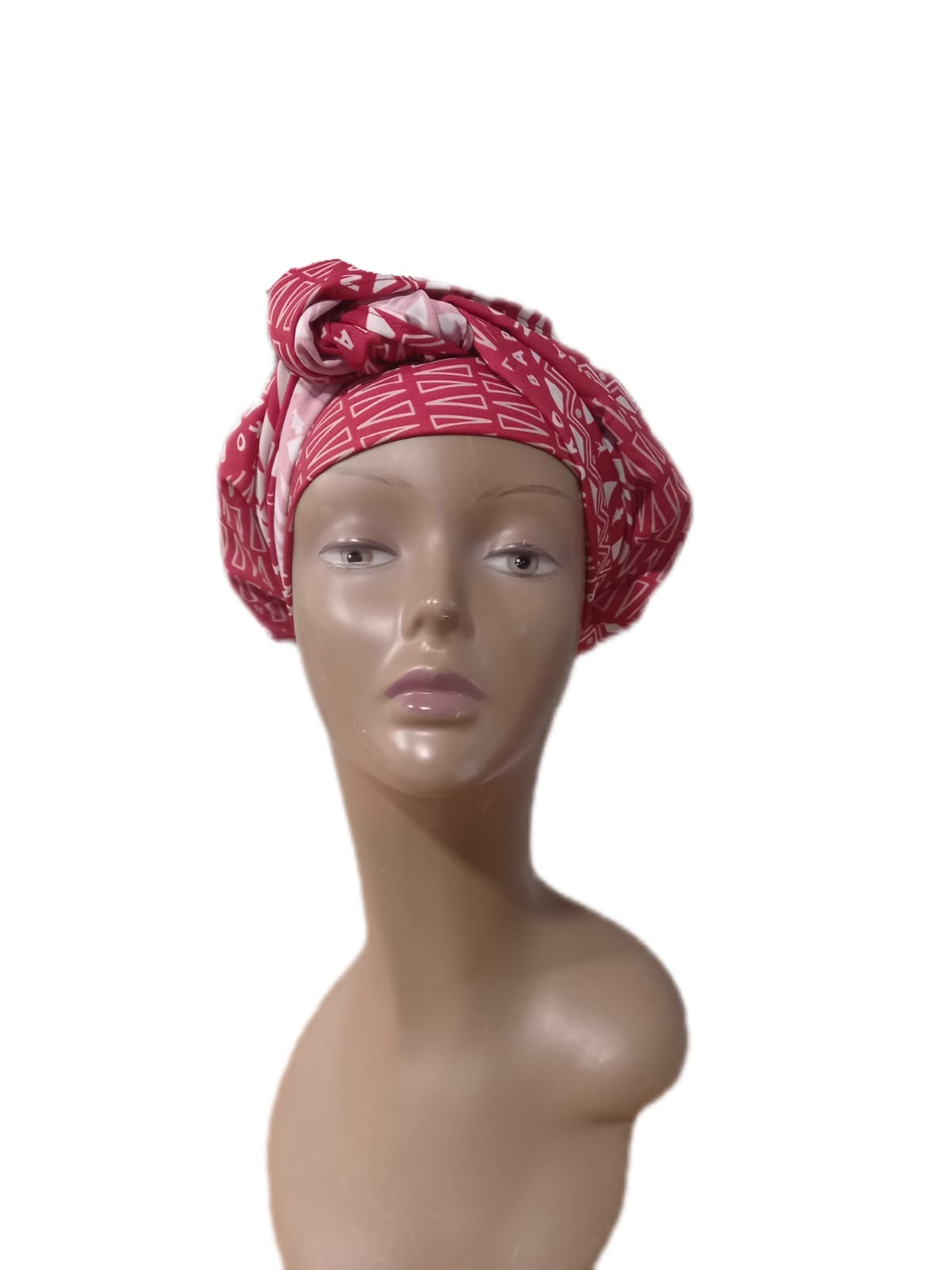 Mannequin head wearing a red patterned headscarf on a white background